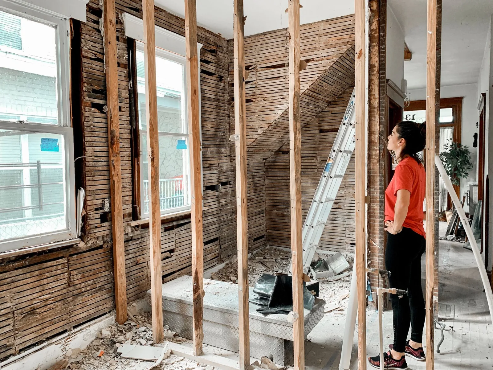 Pessoa inspecionando um interior residencial com paredes abertas e estrutura exposta.